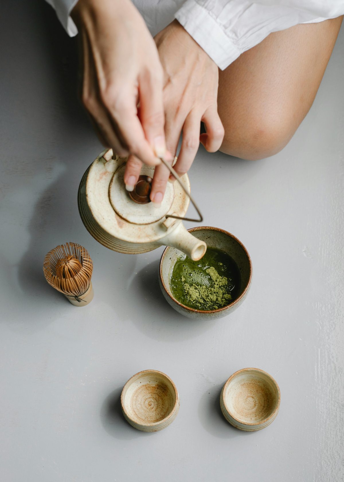 hands-pouring-matcha-tea-mugs